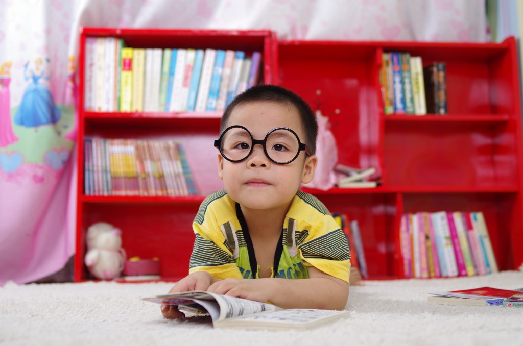 child in black o-shaped glasses reading a book