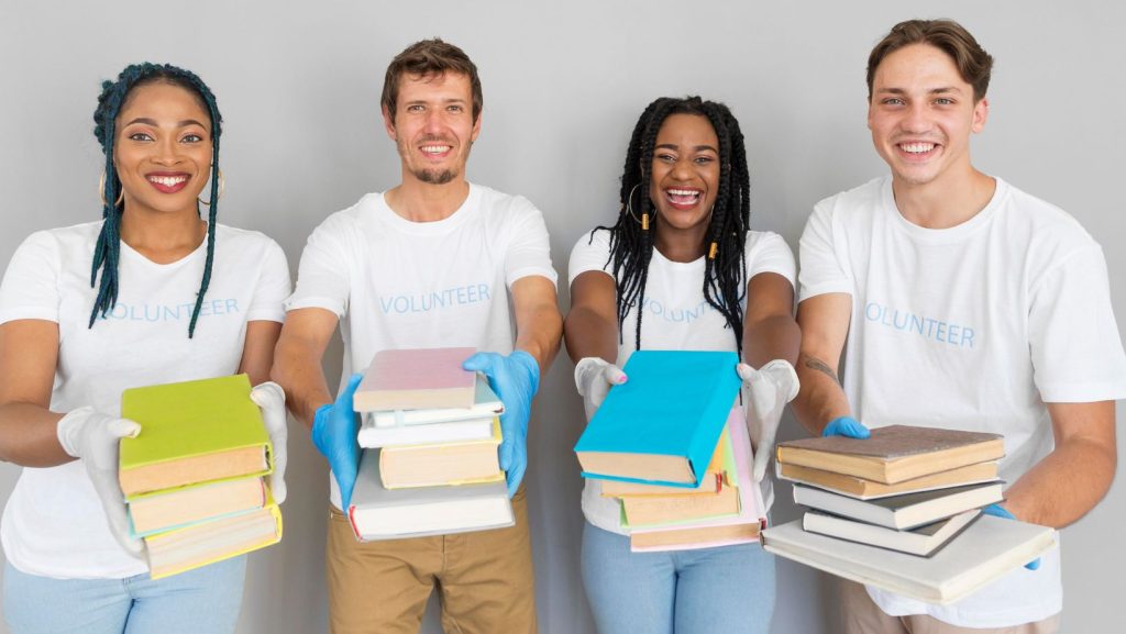 four people carrying a stack of books